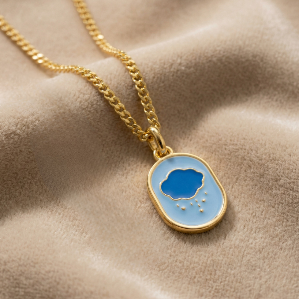 Yellow gold Necklace with a blue enamel Care Beas Grump Bear Belly badge icon pendant featuring a cloud design on a beige fabric background by Couture Kingdom