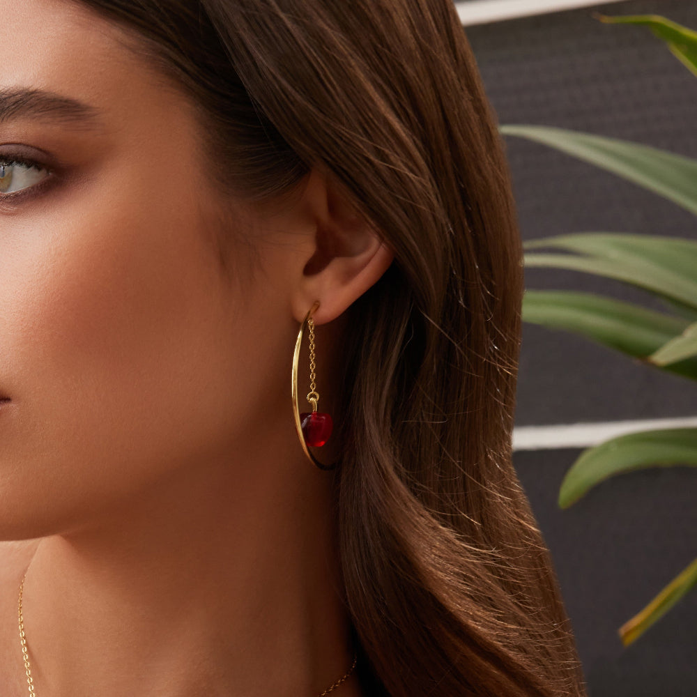 Yellow gold plated Couture Kingdom Disney Snow White Poison Apple Hoop Earrings worn on model with green leaves in background