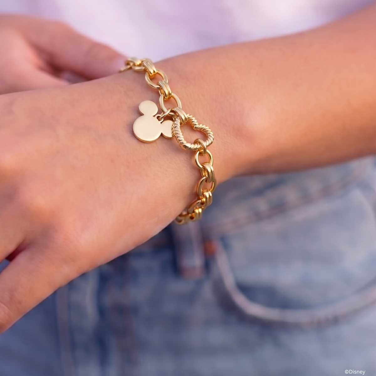 Yellow gold plated medium chunky bracelet with a heart clasp and Mickey Mouse charm worn on wrist