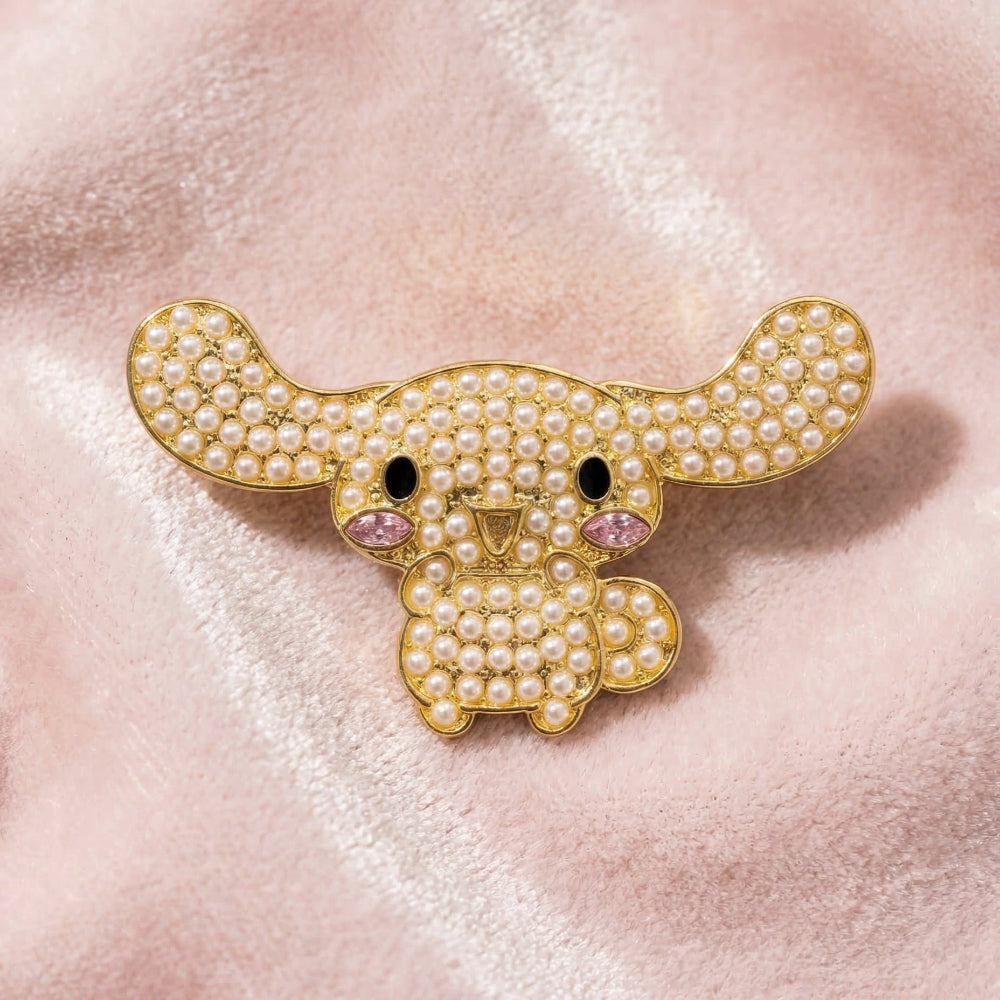 Gold plated Cinnamoroll brooch with pearl and cystal details on a pink textured background by Couture Kingdom