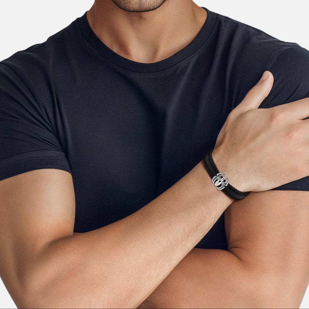 Man wearing a black t-shirt and a black leather bracelet with a silver Spider-Man symbol by Couture Kingdom with a white background