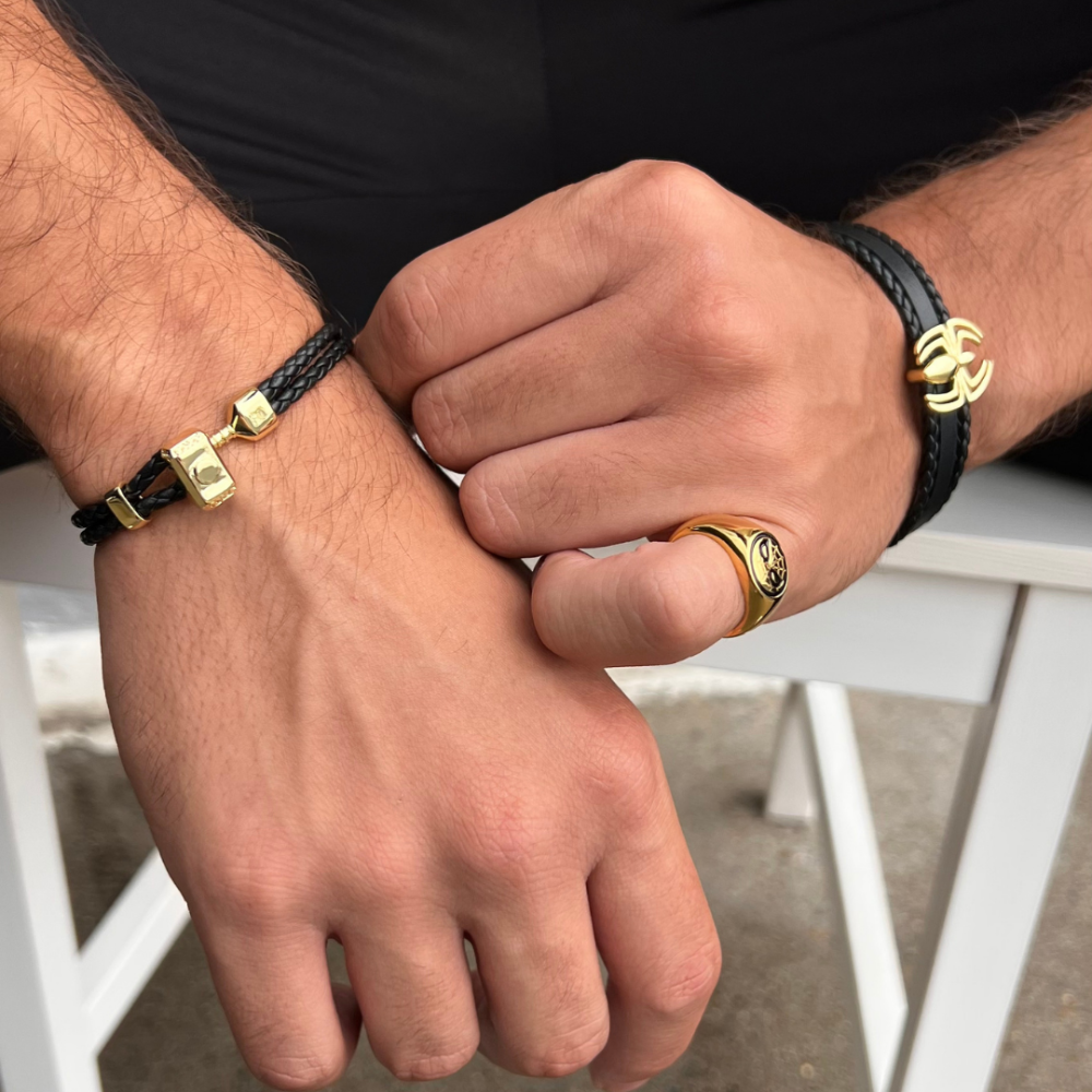 Close up of Marvel braided Leather bracelet with gold plated Thor Hammer worn on male wrist with other wrist wearing a leather Marvel Spider Man bracelet and gold plated spider man ring by couture kingdom