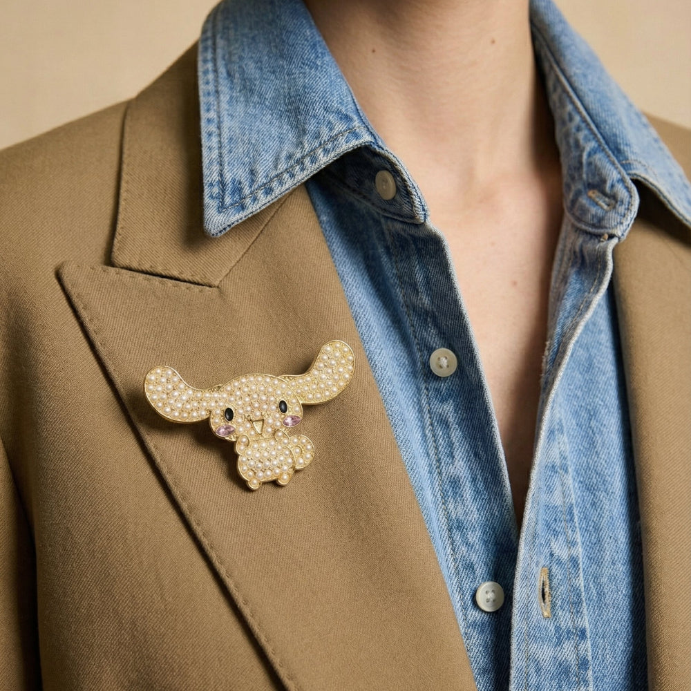 Person wearing a brown coat with a decorative Cinnamoroll brooch and a denim shirt underneath.