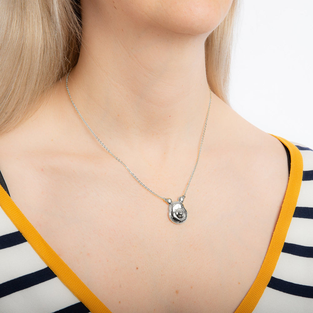 white gold necklace with Disney Winnie The pooh pendant worn on model wearing a black and white strip top against a white neutral background